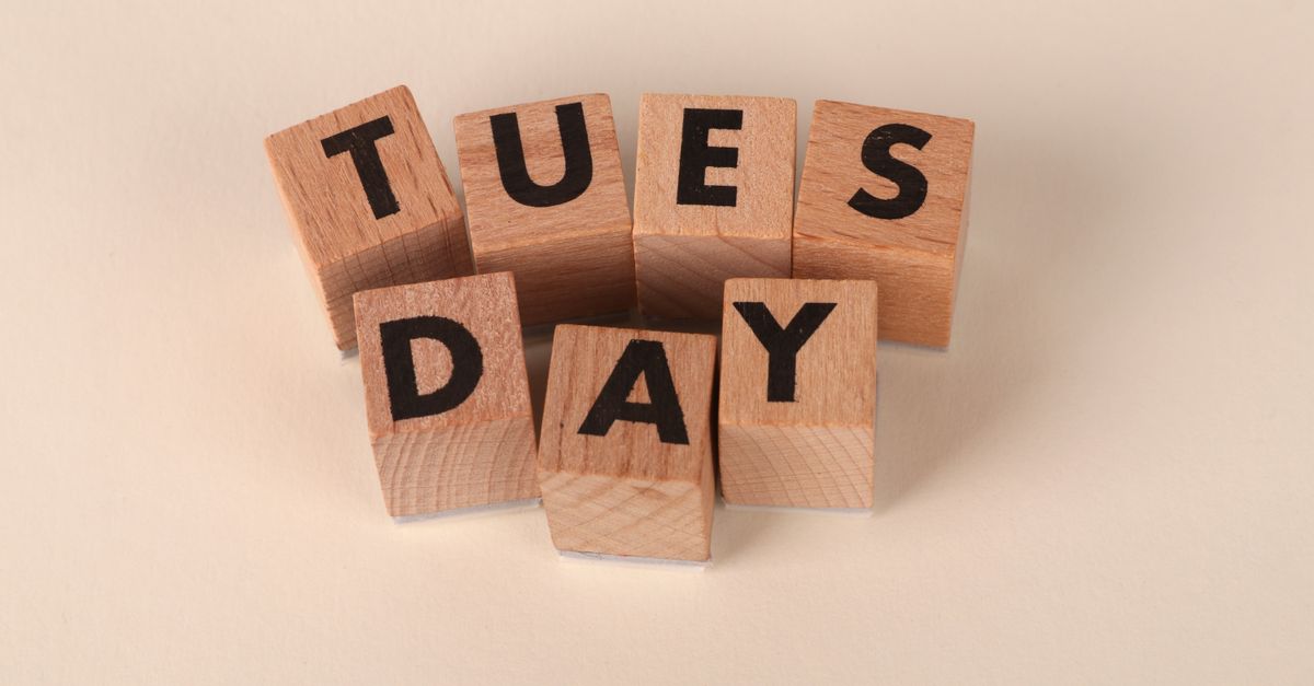 Wooden blocks arranged to spell 'Tuesday' on a beige background.
